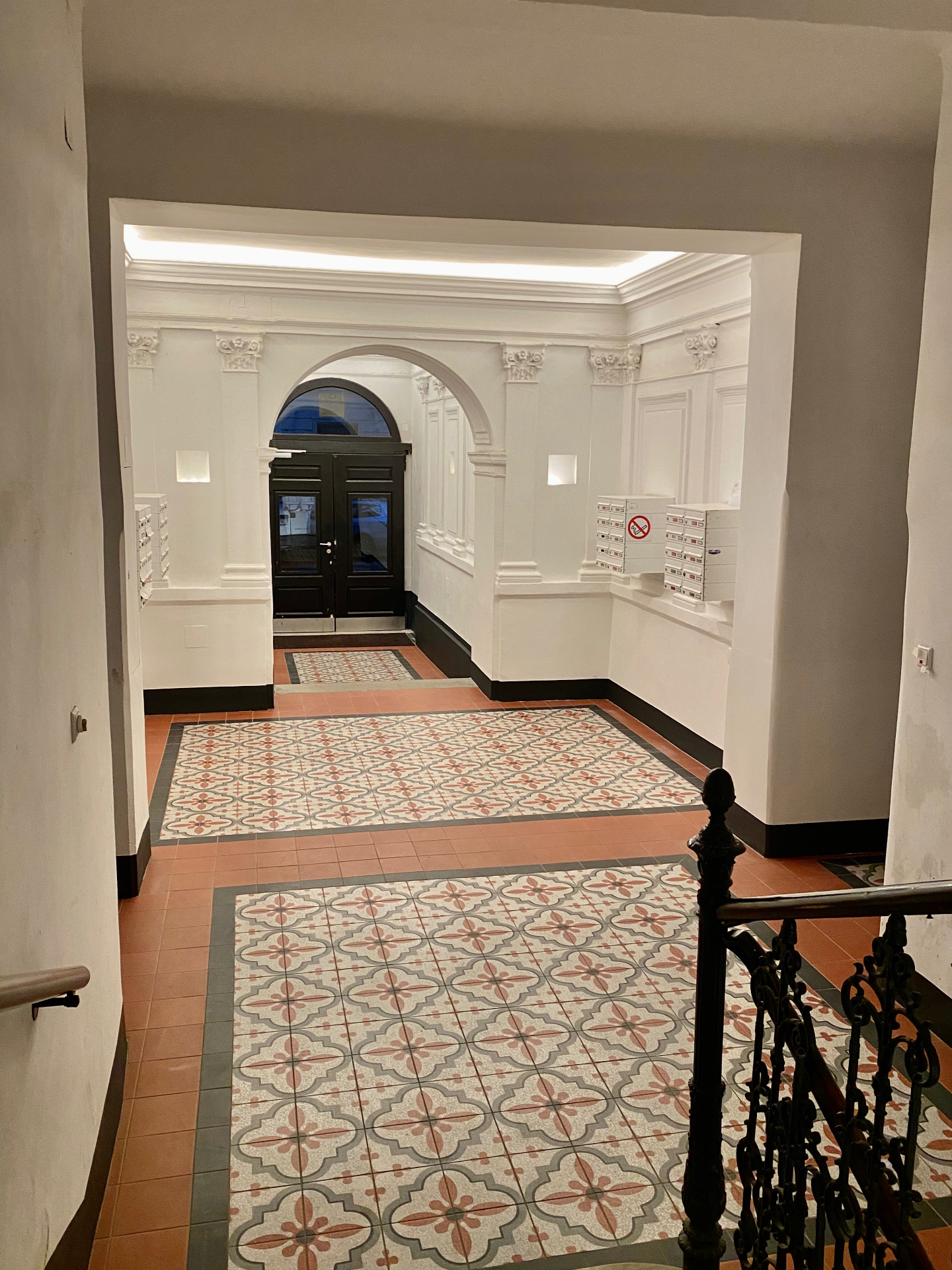 Eingangshalle mit originalen Gründerzeit-Zementfliesen, Stuckpilastern und historischer Rundbogentür